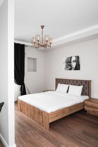 a bedroom with a bed with white sheets and a chandelier at Deluxe Park Z hotel in Almaty