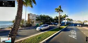 a white car parked on a street next to the ocean at La Perla Playa apartamento a estrenar in Benalmádena