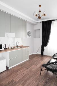 a kitchen with white cabinets and a wooden floor at Deluxe Park Z hotel in Almaty