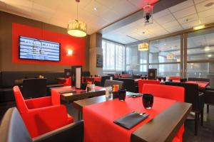 a restaurant with red chairs and tables and a tv at Best Western Plus Paris Orly Airport in Rungis