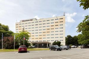 un gran edificio blanco con coches aparcados en un aparcamiento en Best Western Plus Paris Orly Airport en Rungis