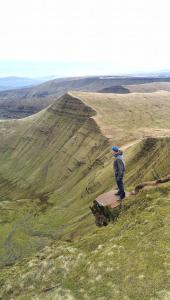 a person standing on a rock on a hill at James' Place at Brynawel in Merthyr Tydfil