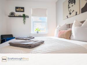 a bedroom with a bed with white sheets and a window at Hampton House - Lovely and Spacious 2 Bedroom Apartment - WITH FREE PARKING in Scarborough