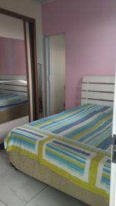 ein Bett mit einer gestreiften Decke in einem Schlafzimmer in der Unterkunft Equilibra Soul in Caraguatatuba