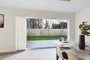 a white dining room with a table and a fence at The Grange Sleeps 8 Family Retreat Free Wi-Fi & Parking in Cheltenham