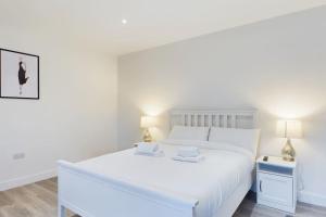 a white bedroom with a white bed and two lamps at The Grange Sleeps 8 Family Retreat Free Wi-Fi & Parking in Cheltenham