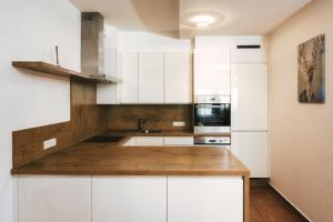 cocina con armarios blancos y encimera de madera en Apartment Alpenherz en Ried im Oberinntal
