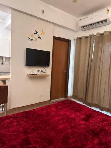 ein Wohnzimmer mit einem TV und einem roten Teppich in der Unterkunft Khushi Home Inn in Noida