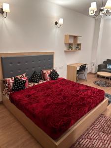 ein Schlafzimmer mit einem großen Bett mit einer roten Tagesdecke in der Unterkunft Khushi Home Inn in Noida