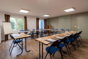 a classroom with long tables and blue chairs at Sure Hotel by Best Western Plaisir in Plaisir
