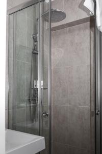 una ducha con una puerta de cristal junto a un lavabo en Deluxe Park Z hotel, en Almaty