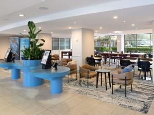 a lobby with tables and chairs and a restaurant at Mercure Sydney Manly Warringah in Sydney