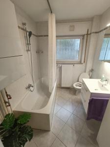 ein Badezimmer mit Badewanne, Toilette und Waschbecken in der Unterkunft Geräumige helle Wohnung im grünen Taunus mit Privatparkplatz in Schlangenbad