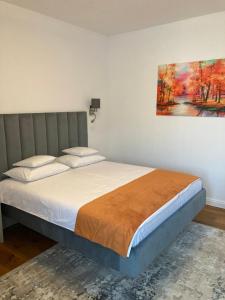 1 dormitorio con 1 cama con una pintura en la pared en Pensiunea Magic en Băile Govora