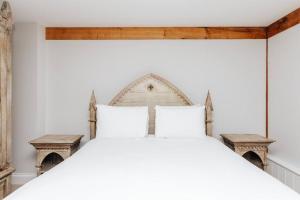 a bedroom with a white bed with two benches at Bix Lodge in Henley on Thames