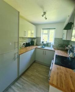 a kitchen with white cabinets and a wooden counter top at Two Bedroom Apartment in South Somerset in Wincanton