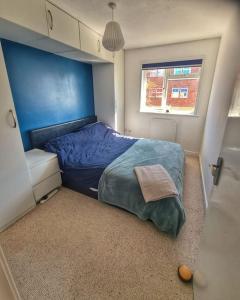 a bedroom with a blue bed and a window at Two Bedroom Apartment in South Somerset in Wincanton