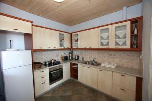 a kitchen with wooden cabinets and a white refrigerator at Anna's Home in Batsi