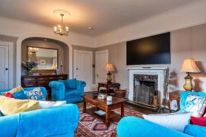 a living room with blue furniture and a fireplace at Finest Retreats - The Old Counting House in Gweek