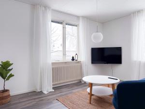 sala de estar blanca con mesa y TV en Rosen, en Nässjö