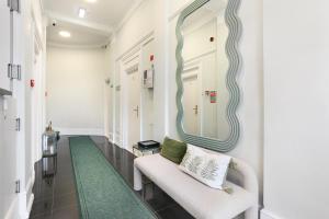 a hallway with a white chair and a mirror at BeiRoom Hyde Park Apartments in London