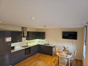a kitchen with black cabinets and a table with chairs at Town center modern apartment 10 in Ipswich