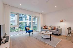 a living room with a couch and a table at Immaculate new 1 bed AC & pool Chelsea in London