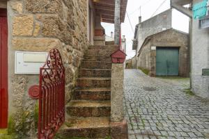 un ancien bâtiment en pierre avec une clôture rouge et des escaliers dans l'établissement Rustic Getaway in Guarda, à Gouveia