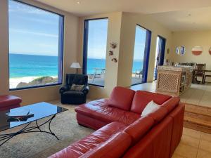 ein Wohnzimmer mit einer roten Couch und dem Meer in der Unterkunft Casita Alegra Beachfront family friendly in Port Elliot