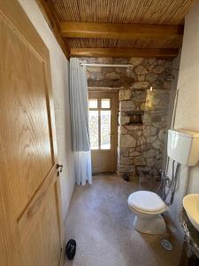 a bathroom with a toilet and a window and a door at Phisis Nature Retreat in Donoussa