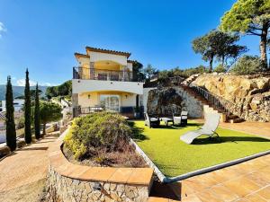 ein Haus auf einem Hügel mit einem Garten mit Stühlen in der Unterkunft Aurea CostaBravaSi in Sant Feliu de Guixols