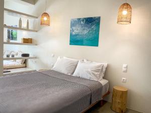 een slaapkamer met een bed met witte kussens en 2 verlichting bij Kynthia Suite - Escape to Seaside Makry Gialos in Makry Gialos