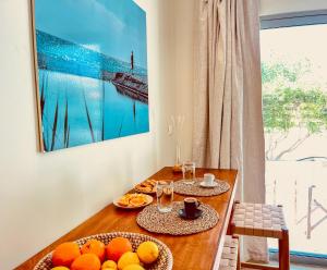 una mesa de comedor con naranjas y copas de vino en Kynthia Suite - Escape to Seaside Makry Gialos en Makry Gialos