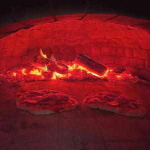 two pizzas are being cooked in a brick oven at Eco Lodge St Ignatius Еко лодж Игнажден in Debelets