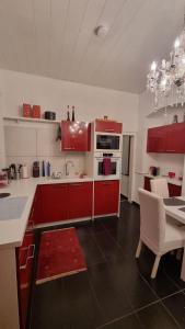 eine Küche mit roten Schränken und einem Tisch mit einem Esszimmer in der Unterkunft Apartment Geibel T4 - 85m2 - Highspeed Internet - Hundefreundlich in Wien