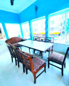 comedor con mesa, sillas y ventanas en Goroomgo Bidisha-2 Digha - Excellent Stay with Family, Parking Facilities, en Digha