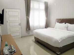 ブキティンギにあるVilla Victoria Bukittinggiのベッドとテーブルと窓のある寝室