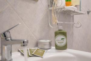 a green bottle of soap sitting on a bathroom sink at Piombino Apartments - Casa Mirò in Piombino