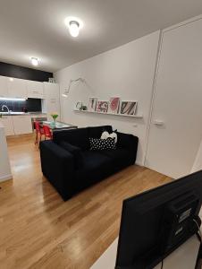 sala de estar con sofá negro y cocina en Confortevole bilocale Empoli, en Empoli