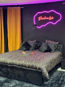 - un lit avec un panneau de néon sur le mur dans l'établissement LoveRoom by Sunnyroom, à Perpignan
