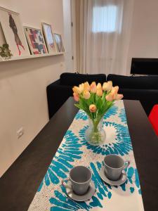 un jarrón de flores sentado en una mesa con dos tazas en Confortevole bilocale Empoli, en Empoli