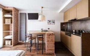 a kitchen with a counter and stools in a room at Residence Antares in Selva di Val Gardena