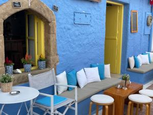 a patio with chairs and tables in front of a blue building at Kynthia Suite - Escape to Seaside Makry Gialos in Makry Gialos