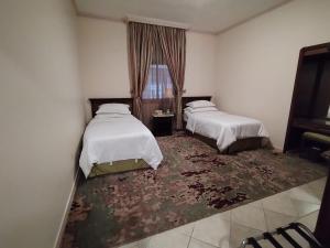ein Hotelzimmer mit 2 Betten und einem Teppich in der Unterkunft فندق روتانة الحمراء in Dschidda