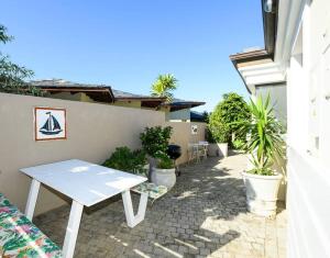 a white picnic table on a patio with plants at Modern 1 bedroom non-seafacing unit on luxury golf estate in Knysna