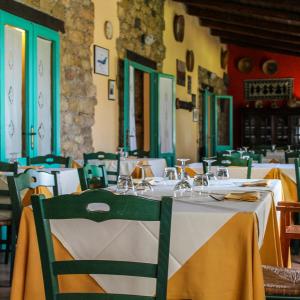 uma sala de jantar com mesas brancas e cadeiras verdes em Hotel Sa Lolla em Barumini