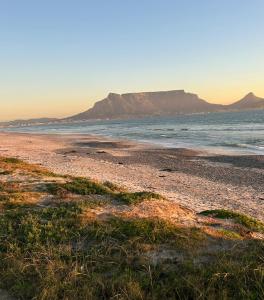 a beach with a view of the ocean and a mountain at Sunset Waves Bloubergstrand in Sunset Beach