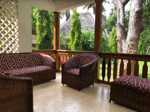 eine Veranda mit 2 Stühlen, einem Tisch und einem Baum in der Unterkunft Petwac Oasis in Malindi