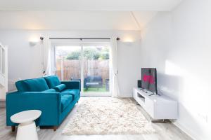 Stylish Retreat in Nuneaton Centre with Sofa Bed, Garden and Super Fast Wi-Fi في نيونياتون: غرفة معيشة مع أريكة زرقاء وتلفزيون