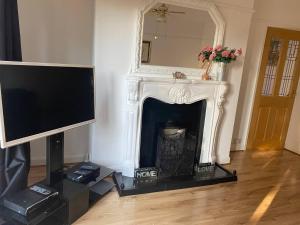 a living room with a tv and a fireplace at The Gold- Home away from home in Manchester